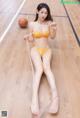 A woman in a yellow lingerie sitting on a basketball court.