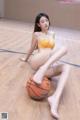 A woman sitting on a basketball on a wooden floor.