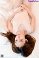 A woman laying on top of a white bed.