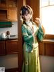 A woman in a green dress standing in a kitchen.