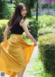 A woman in a black top and a yellow skirt.