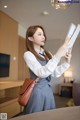 A woman in a school uniform holding a book.