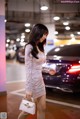 A woman in a silver dress standing next to a car.