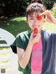 A young woman holding a strawberry in front of her face.