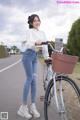 A woman standing next to a bike with a basket on the back.