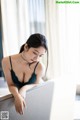 A woman in a black lingerie sitting on a couch.