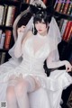 A woman in a wedding dress sitting on a chair.