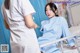 A woman in a hospital room with a nurse standing next to her.