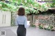 a woman standing in front of a wall of flowers