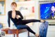 A woman sitting on top of a table in front of a television.