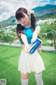 A woman in a blue shirt and white skirt holding a can of soda.