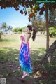 A woman in a colorful dress standing under a tree.