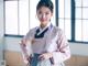 A woman in a pink and blue hanbok posing for a picture.