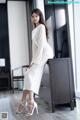 A woman in a white dress sitting on a dresser.