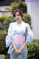 A woman in a blue and pink kimono holding an umbrella.