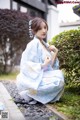 A woman in a blue kimono sitting on the ground.