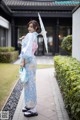 A woman in a blue and pink kimono holding an umbrella.