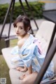 A woman in a blue kimono sitting on a white couch.