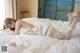 A woman laying on top of a bed in a white dress.