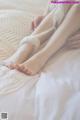 A woman is sitting on a bed with her bare feet.