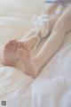 A woman's bare feet on a bed with white sheets.