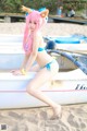 A woman in a bikini sitting on a boat on the beach.