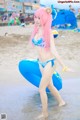 A woman in a bikini standing in the water with a surfboard.