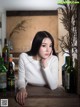 A woman sitting at a table with bottles of wine.