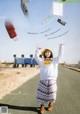 A woman standing on the side of a road holding shopping bags.