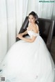 A woman in a wedding dress sitting on a chair.