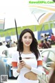 A woman holding an umbrella in front of a car.