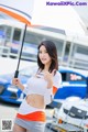 A woman holding an umbrella in front of a race car.