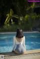 A woman sitting on the edge of a swimming pool.