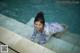 A woman in a bathing suit laying on the edge of a pool.