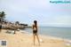 A woman in a black bathing suit standing on a beach.