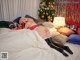 A woman laying on a bed in front of a Christmas tree.