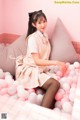 A woman sitting on a bed of pink and white balloons.