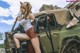 A woman sitting on top of an old military vehicle.