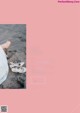 A woman in a white dress sitting on a beach next to a pair of shoes.