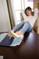 A woman sitting on top of a wooden table next to a book.