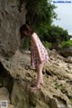 A woman in a floral dress standing on a rock.