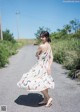 A woman in a white dress is walking down a road.